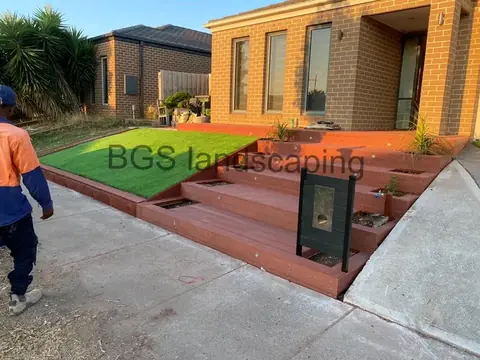 Stepped deck with planter boxes and artificial grass at the front of a tan brick house