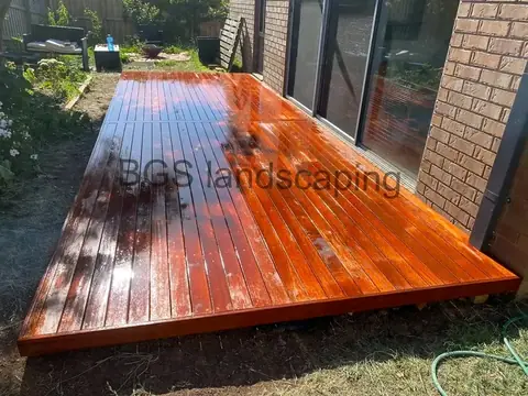 Glossy reddish-brown timber deck against a brick wall with sliding doors
